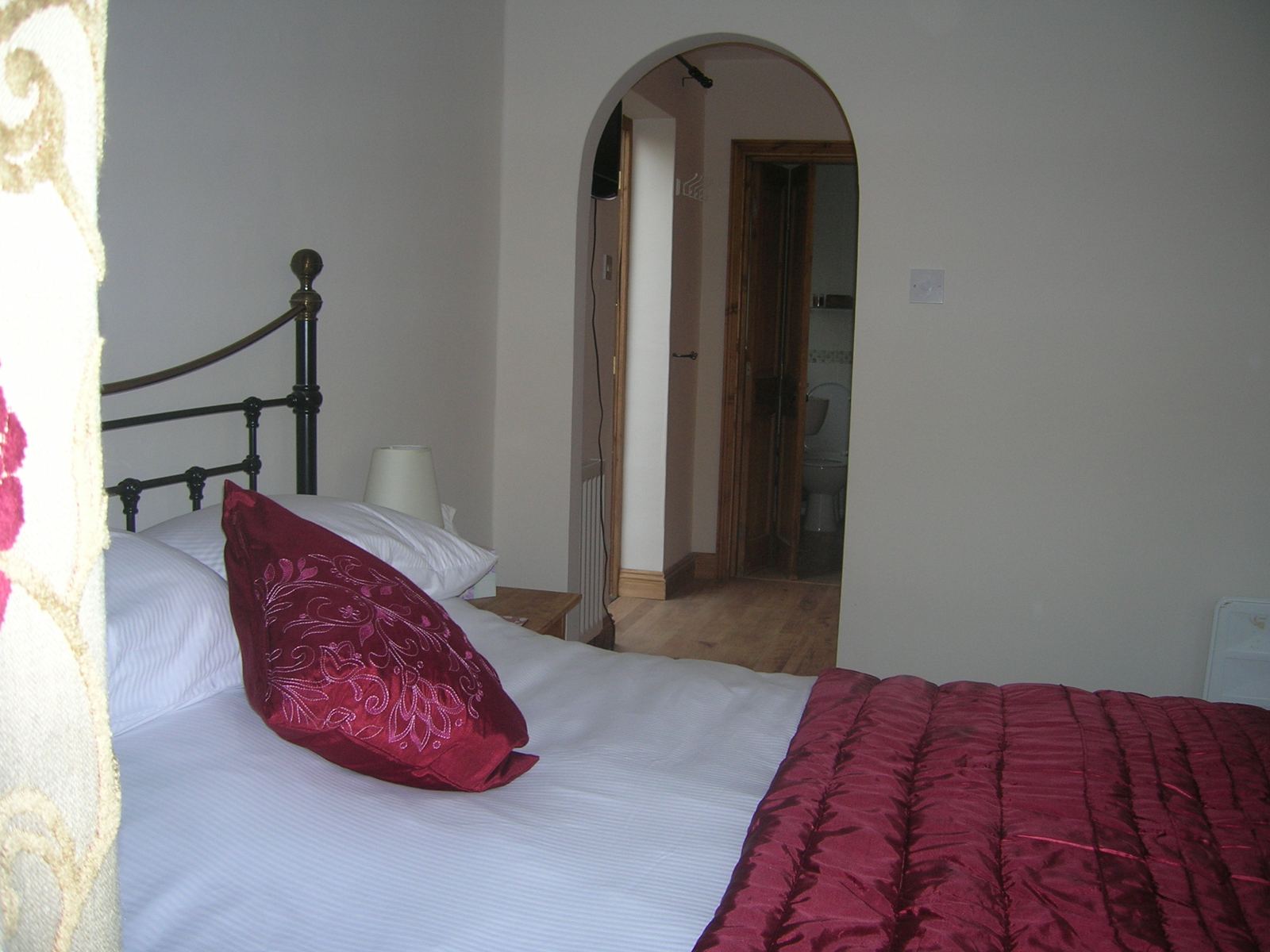 Suite bedroom with iron bedstead, opening through an archway to the en-suite shower room